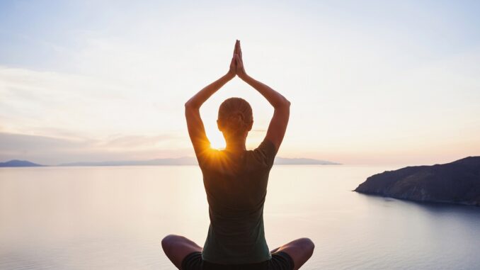 Young woman practicing yoga near the sea at sunset. Harmony, meditation and travel concept. Healthy lifestyle bemestar